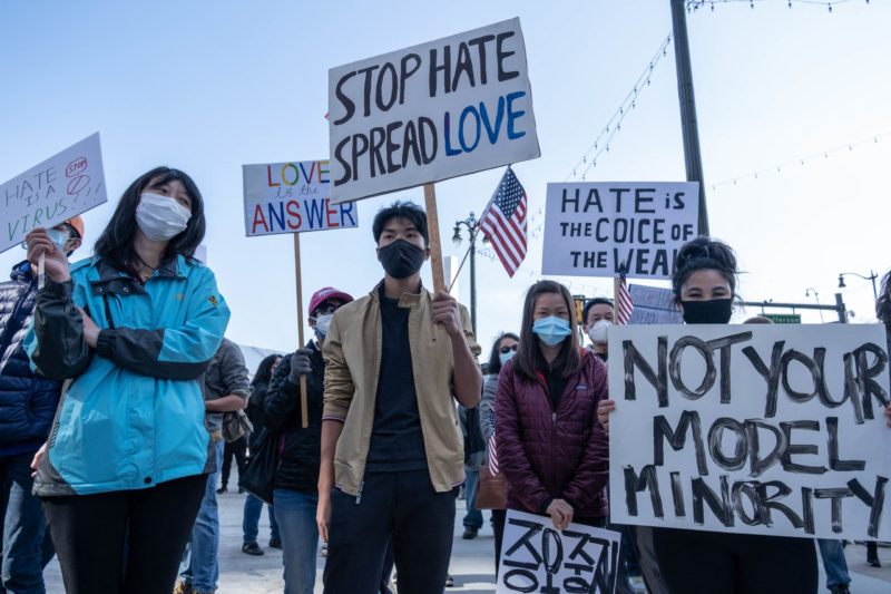 Crowd of Asian people holding signs that say Not Your Model Minority