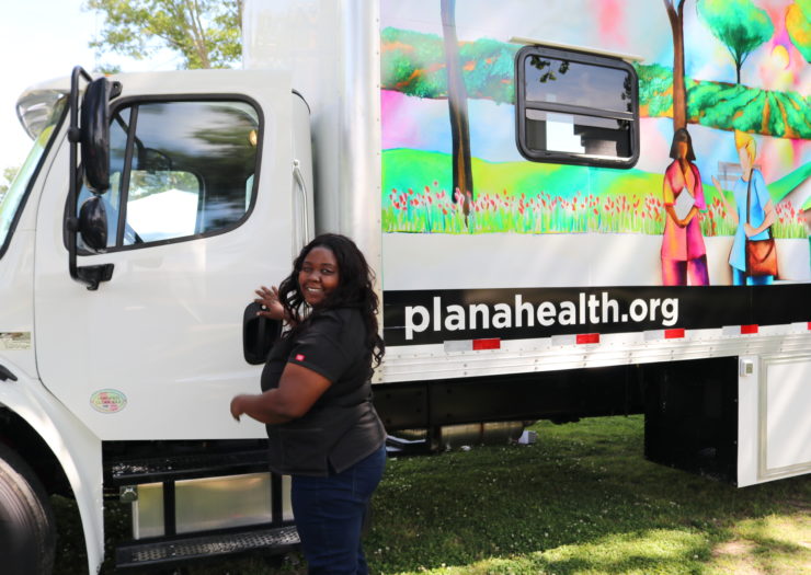 Black woman standing in front of big white truck that says planahealth.org