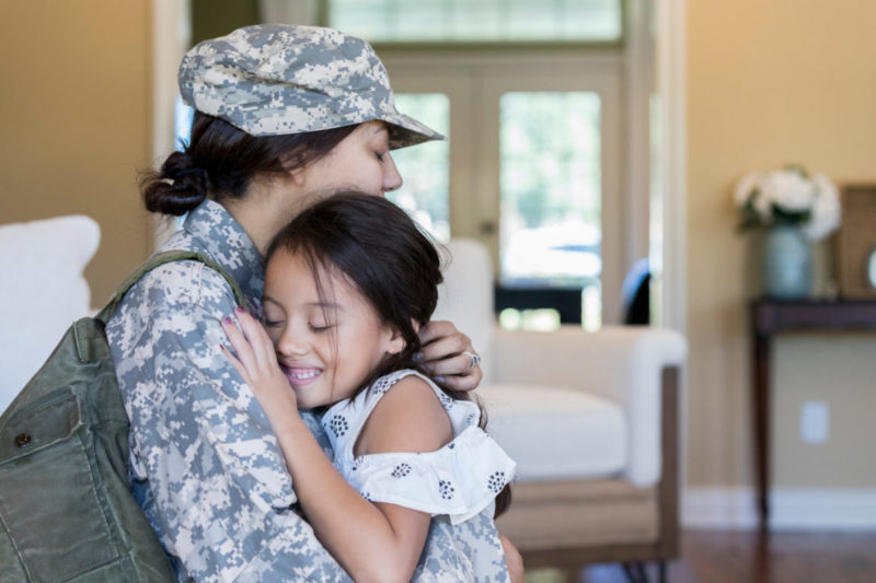 Photo of woman in military gear hugging young girl