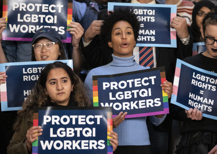 Photo of people holding up signs that say Protect LGBTQI Workers