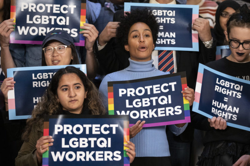 Photo of people holding up signs that say Protect LGBTQI Workers