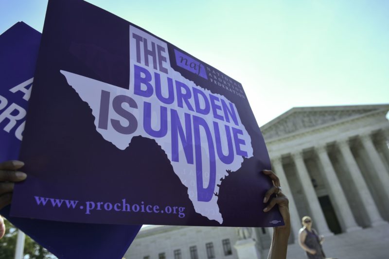 Photo of a sign that reads The Burden Is Undue in the shape of Texas