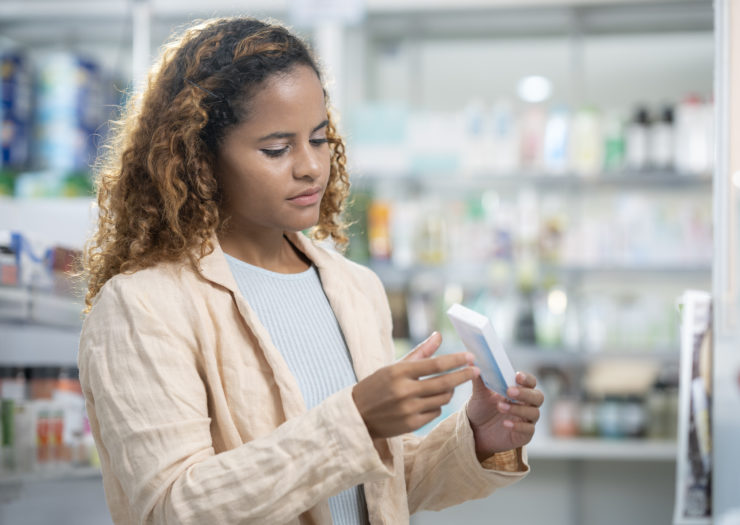 Photo of Black woman at pharmacy holding box of contraceptive pills
