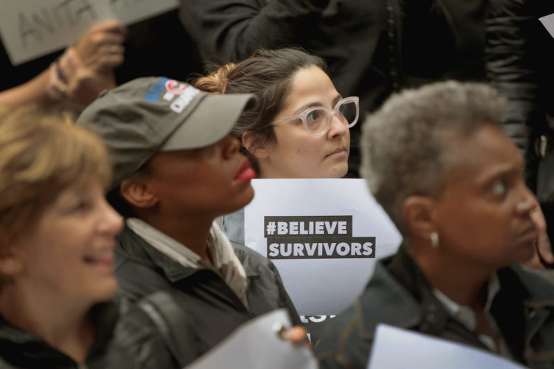 Photo of woman holding a sign that reads #BelieveSurvivors at a protest