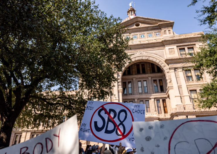 [A sign held up outside the Texas Capitol building shows 