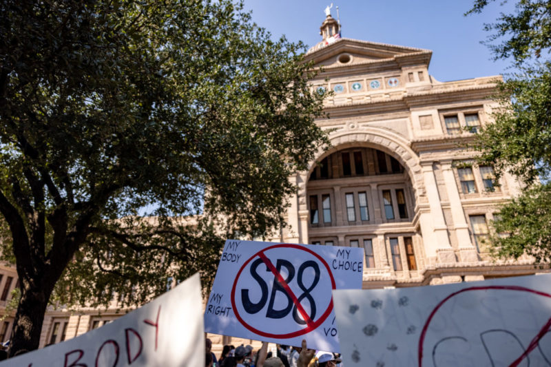 [A sign held up outside the Texas Capitol building shows