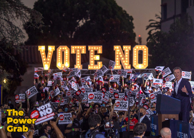 Photo of a big protest with signs and neon letters that spell out vote no