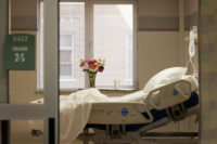Photo of vacant hospital bed in room with flowers and IV bag