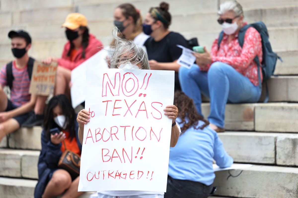 Photo of woman holding up a sign in downtown Brooklyn that reads No!! Texas abortion ban!! Outraged!!