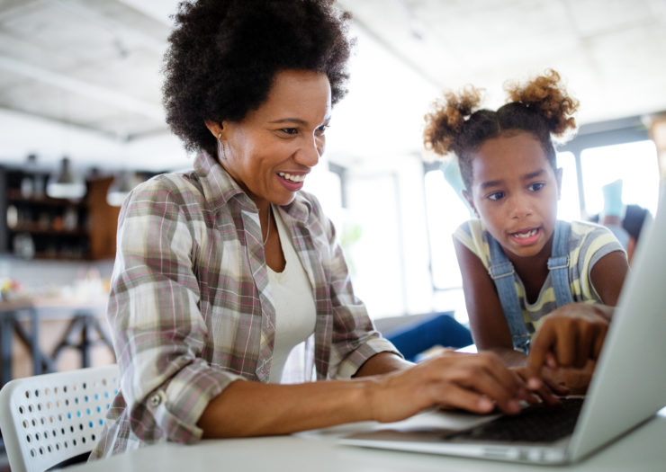 Stock photo of Black woman and kid looking at a laptop while working from home