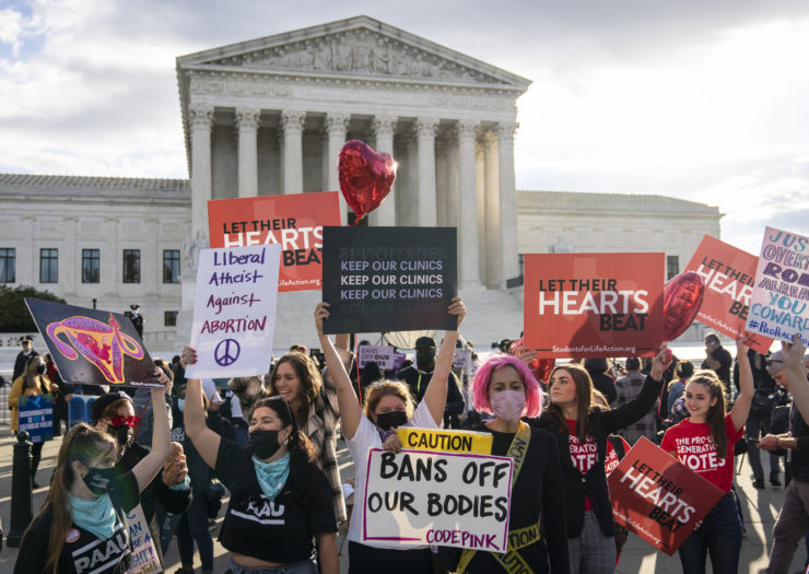Photo d'un militant des droits à l'avortement et de militants anti-avortement manifestant devant le bâtiment de la Cour suprême