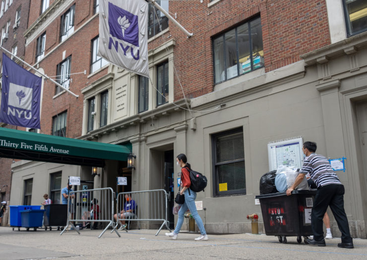 Photo of New York University student moving into Rubin Hall with parent behind them pushing cart of belongings