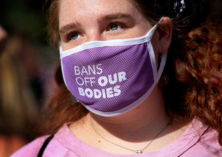 Photo of closeup of young person wearing a purple mask that reads Bans off our bodies