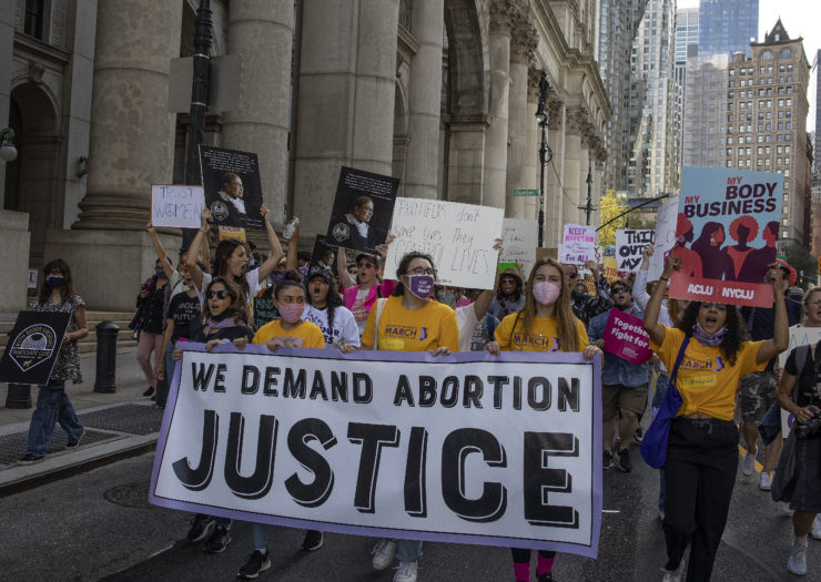 Photo of group of protesters carrying a banner that reads we demand abortion justice