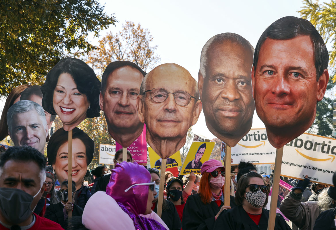 Abortion activists holding photos of Supreme Court justices heads on a stick.