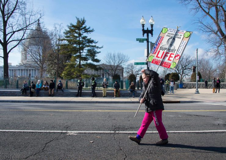 Photo of a young girl marching down an empty street with a sign