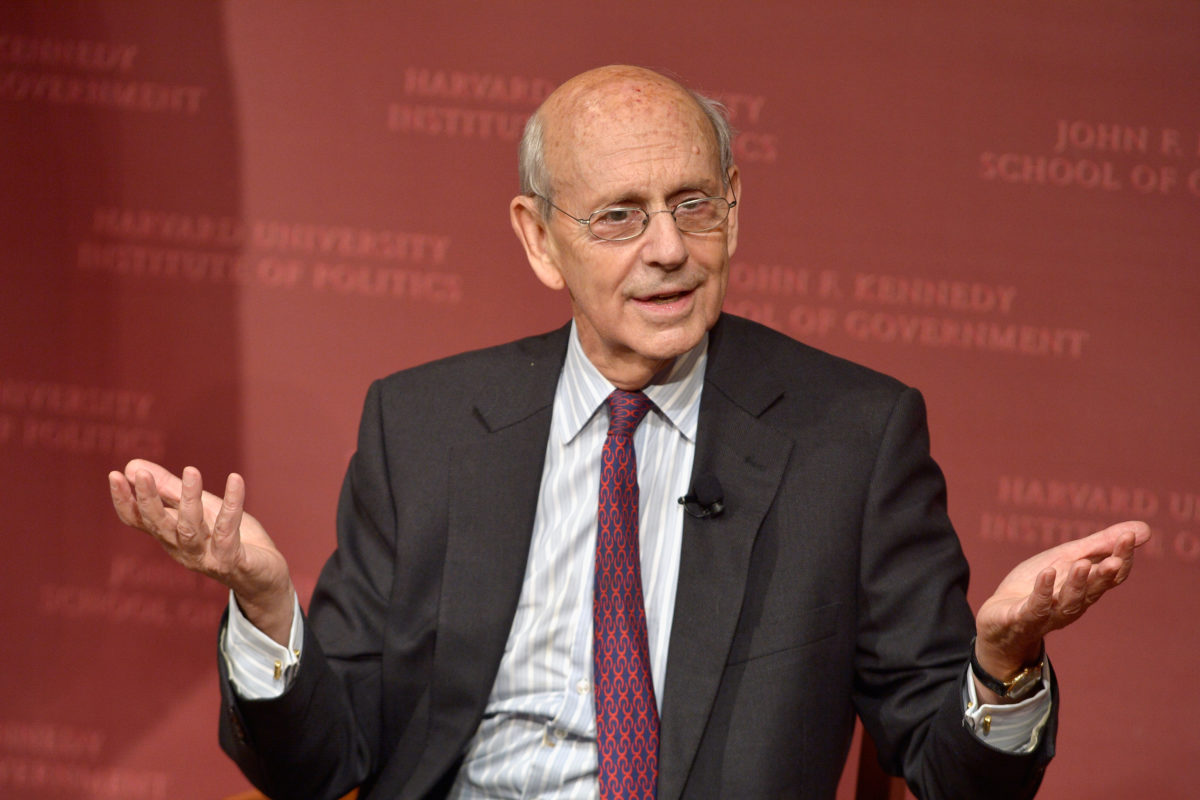 Photo of Justice Stephen Breyer sitting in front of a red background