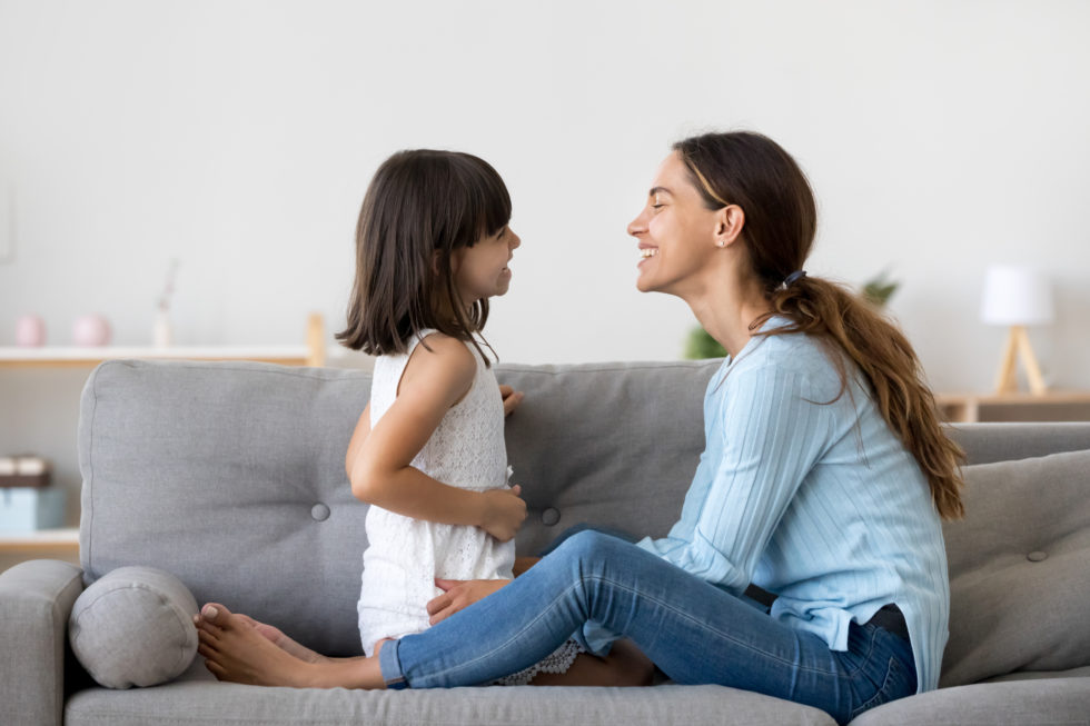 Photo of young girl and mom on the couch talking