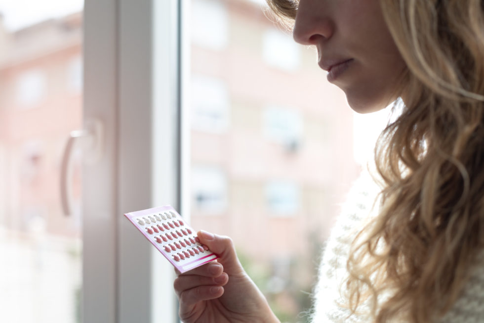 Photo: Close-up image of woman holding birth control pills in a package