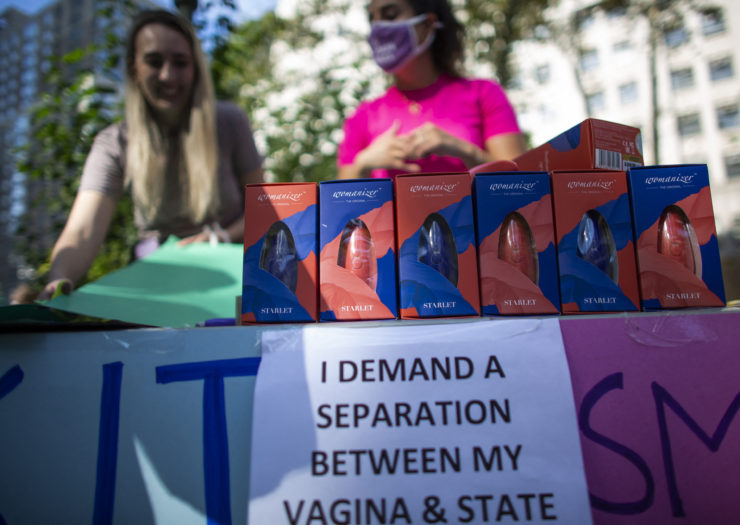 Photo of two volunteers standing behind a table of sex toys to be distributed during an abortion rally