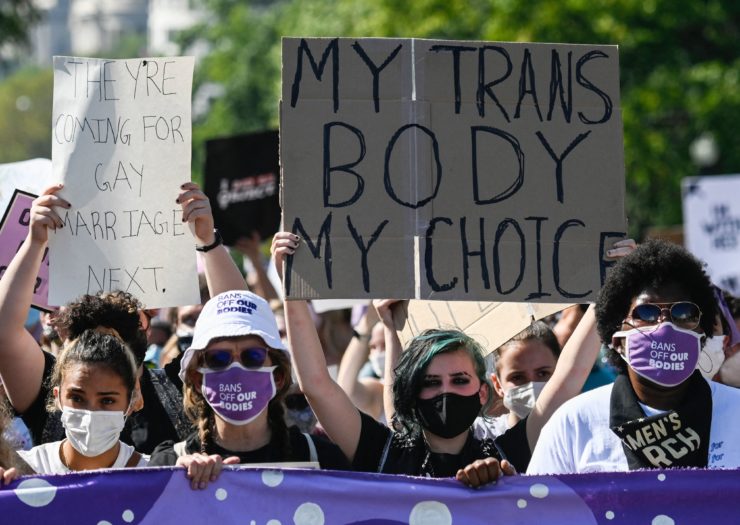 Photo of activist holding sign that says My trans body My choice