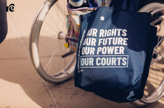 Photo of wheelchair with a bag that reads Our rights, our future, our power, our courts