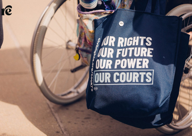 Photo of wheelchair with a bag that reads Our rights, our future, our power, our courts