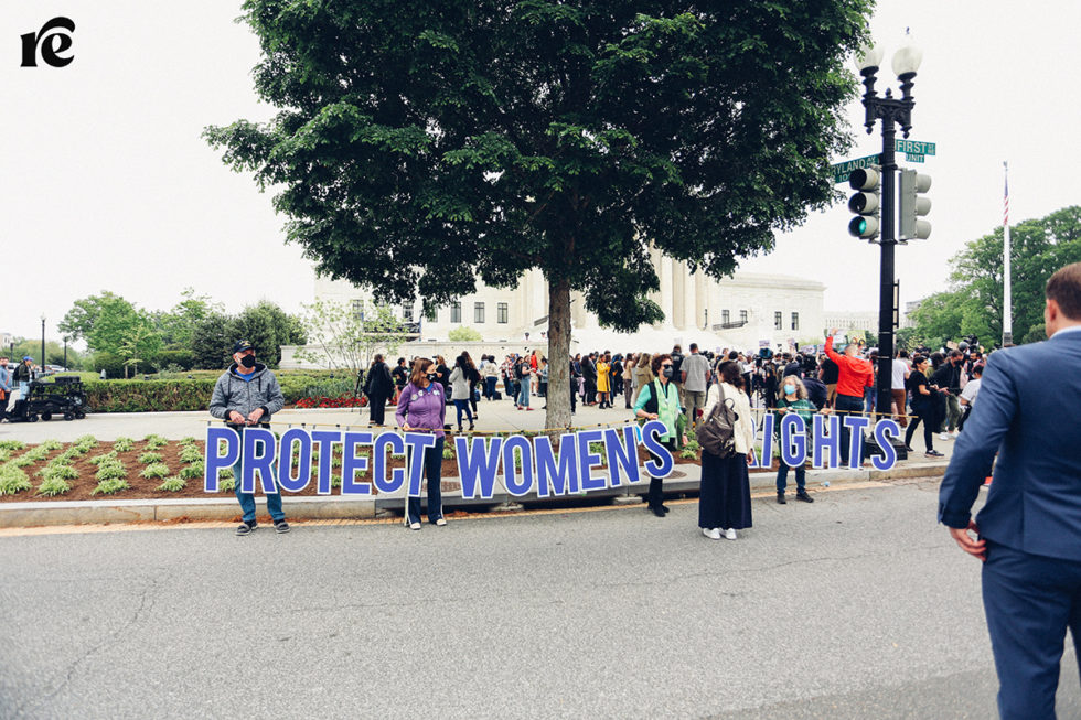 Photo of people holding large sign that reads Protect women's rights