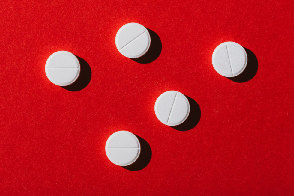 Ttop view of round white pills on red background
