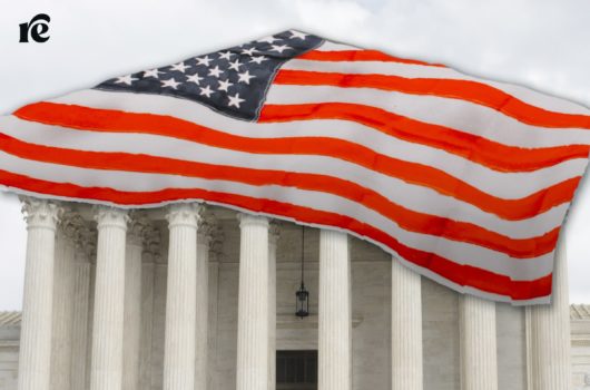 The Supreme Court building covered at the top with an American flag