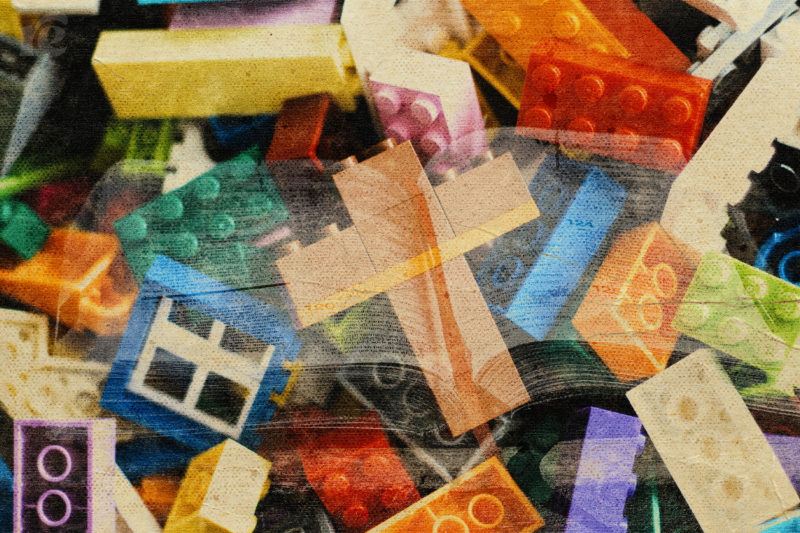 Photo of legos with four pieces held into a cross symbol