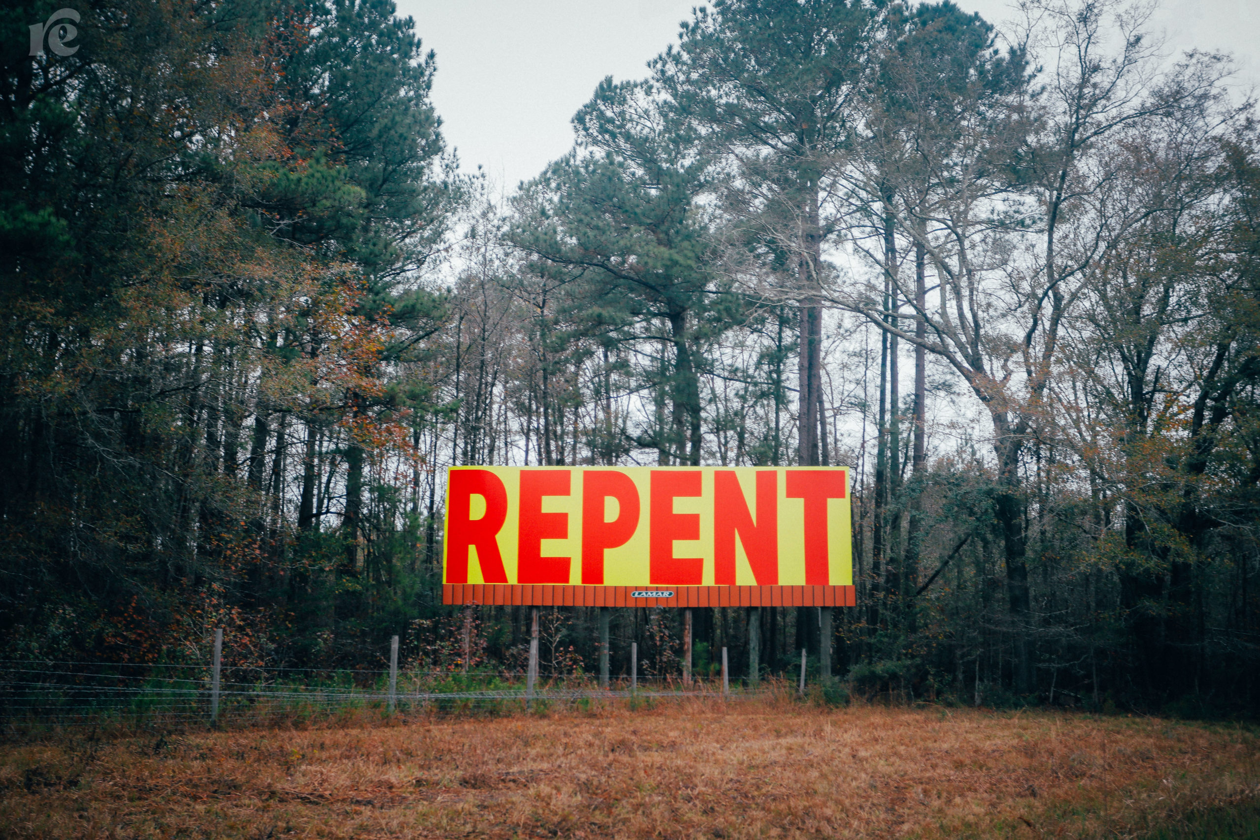 Photo of billboard, background is yellow and Repent is in all caps in red