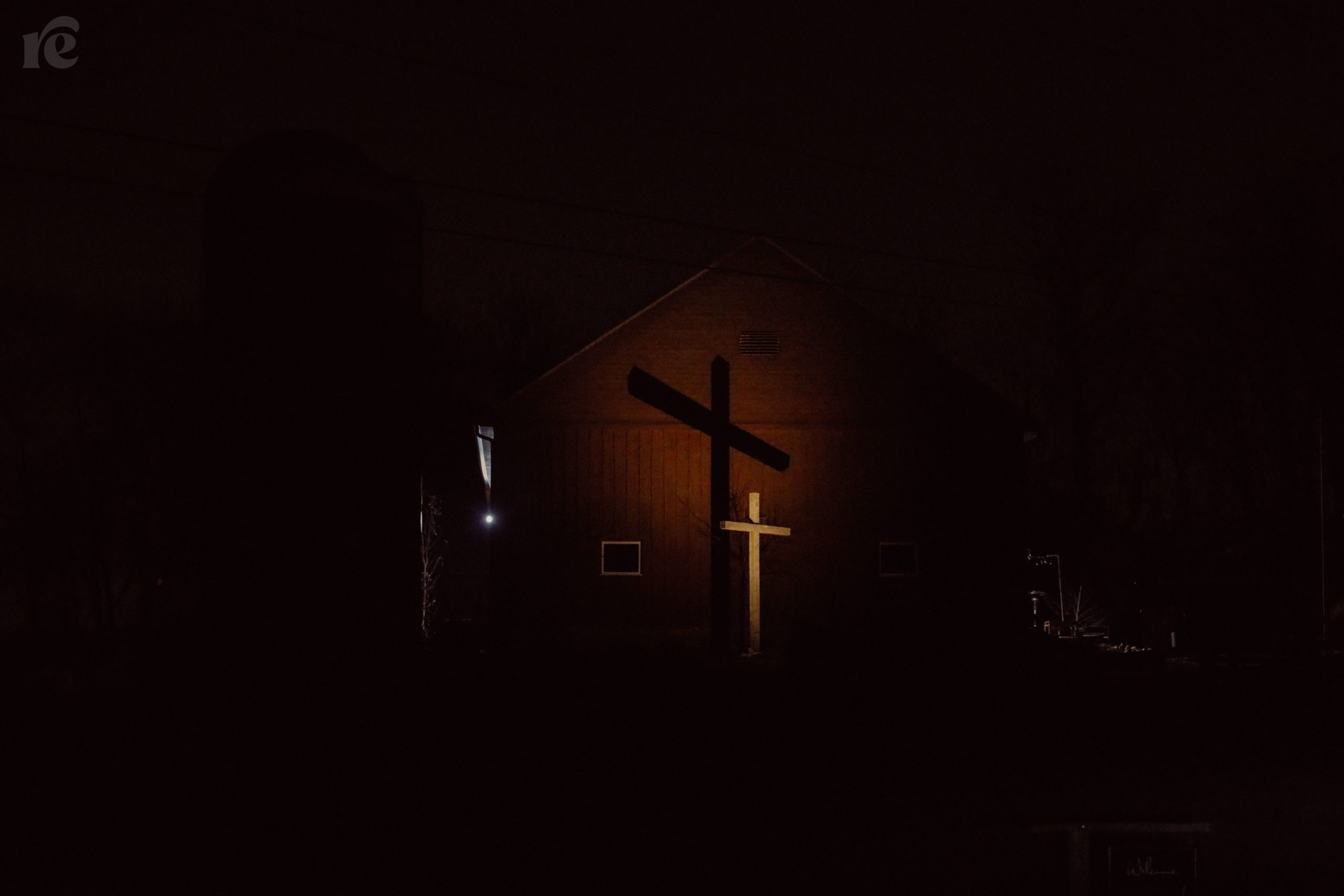 Nighttime image of a cross in front of a barn