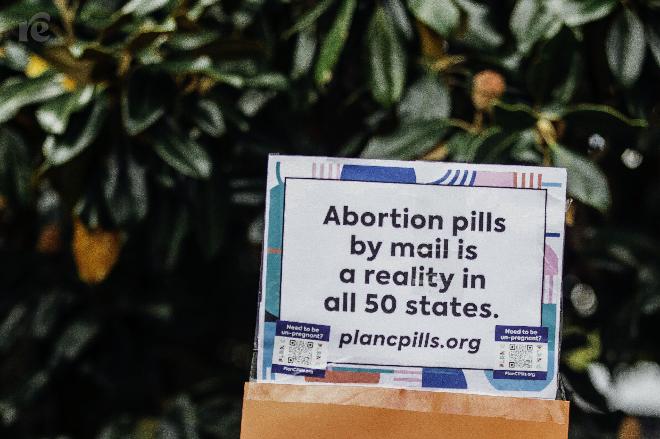 Photo of sign that reads: Abortion pills by mail is a reality in all 50 states. plancpills.org