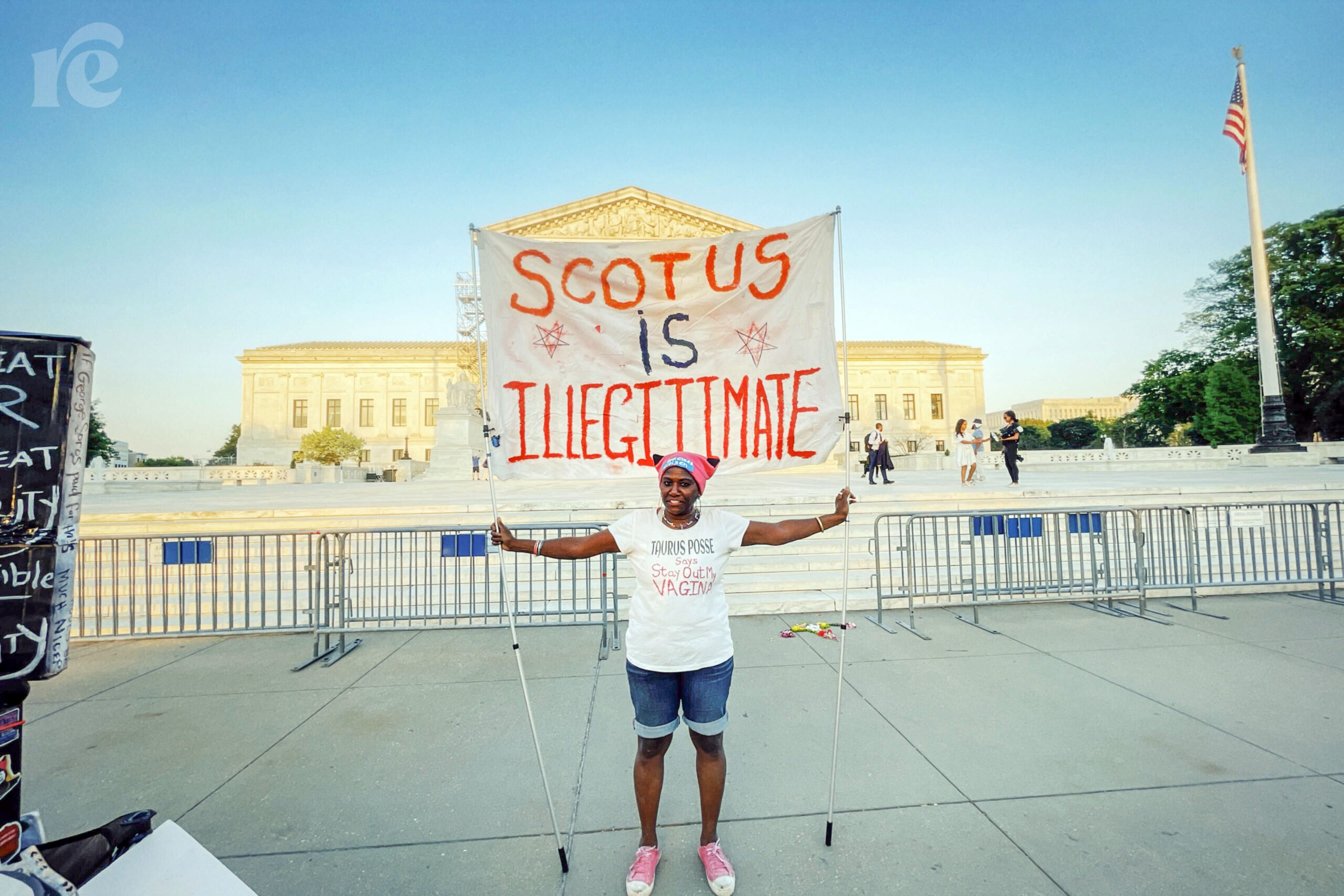 Photo of protester holding sign that says SCOTUS is illegitimate
