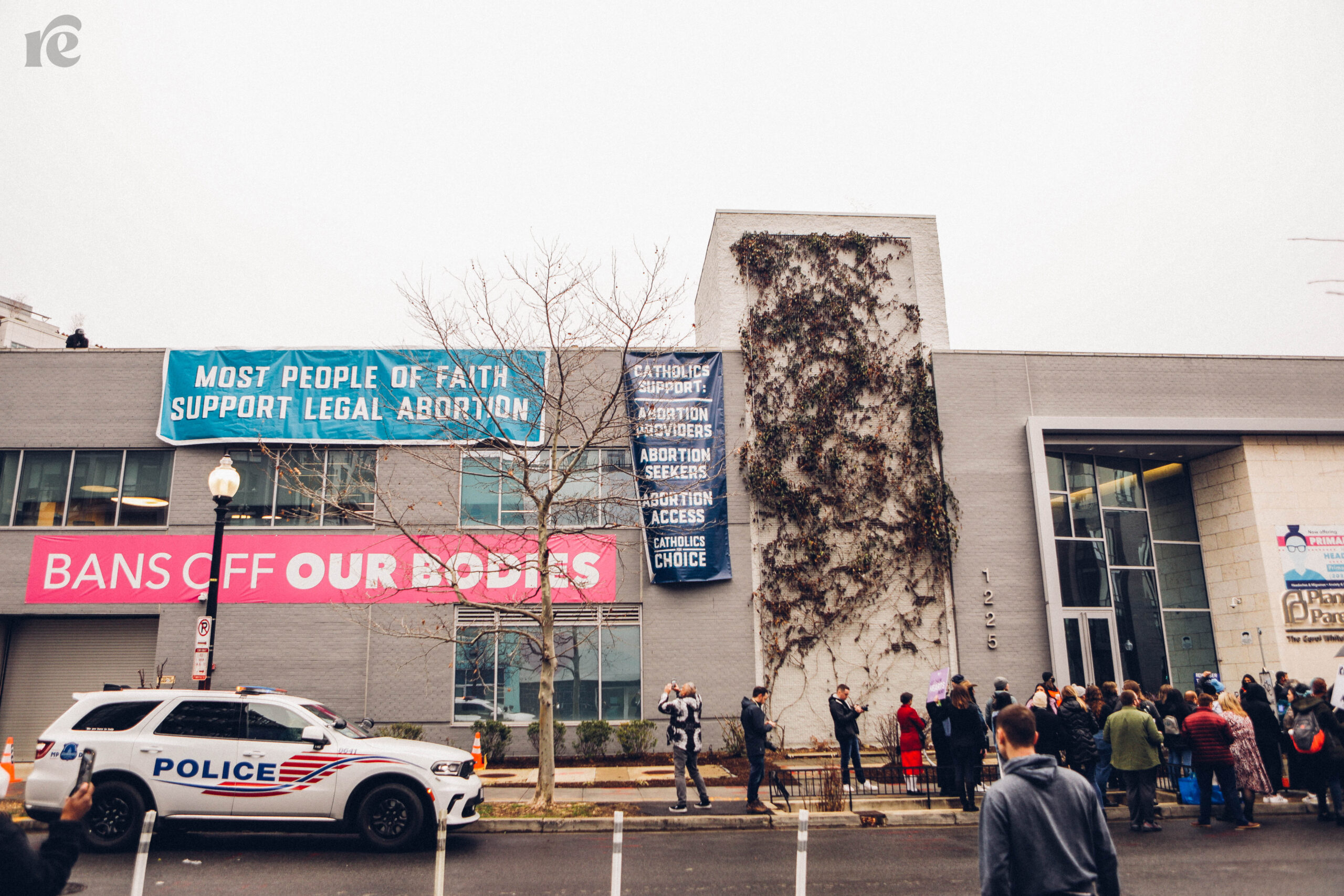 Photo of pro-abortion signs in front of a building with a cop car in front