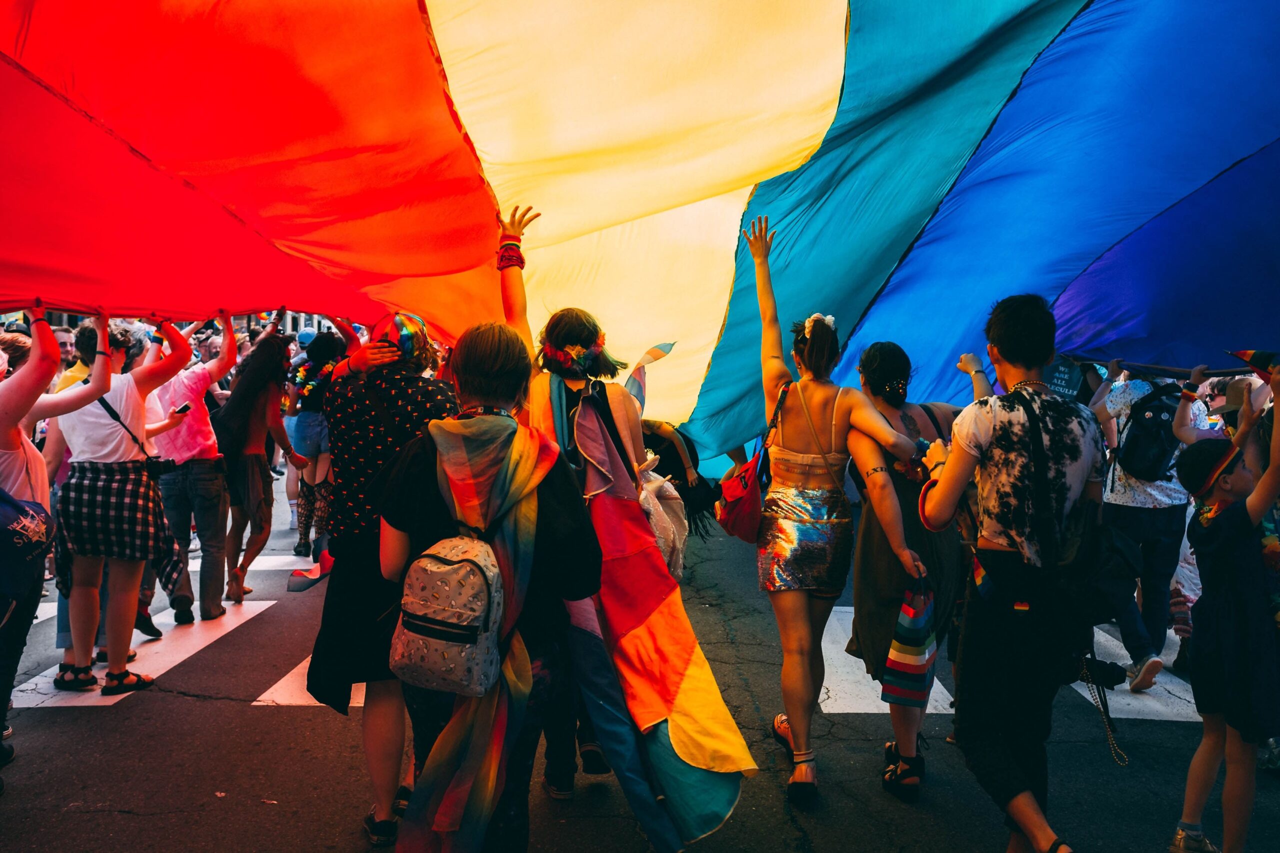 Photo of people gathered under giant Pride flag