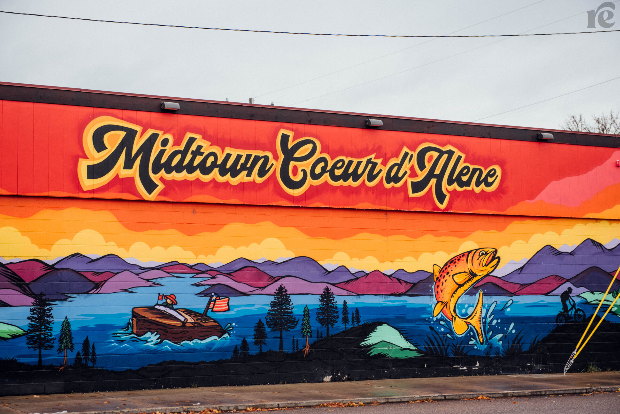 Street art with bright sunset colors and purple mountains that reads Midtown Coeur d'Alene