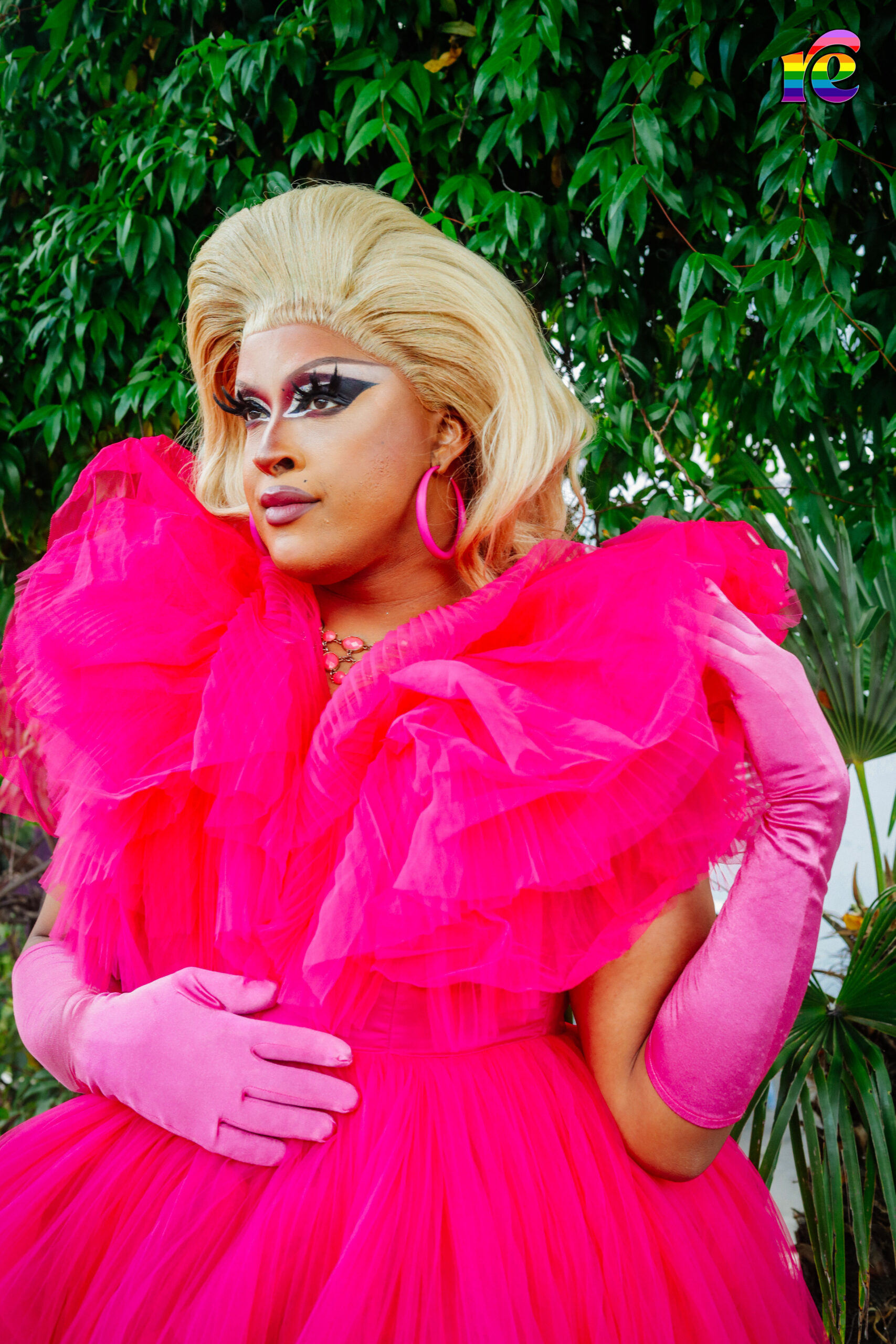 drag queen in pink standing by tree
