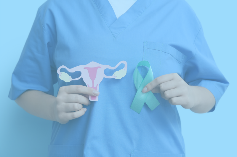 A copped photograph of a medical professional holding up a cut-paper crafted diagram of a uterus in one hand and in the other hand holding a green ribbon. The image has a blue color overlay.