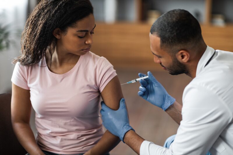 Doctor injects vaccination into female patient.